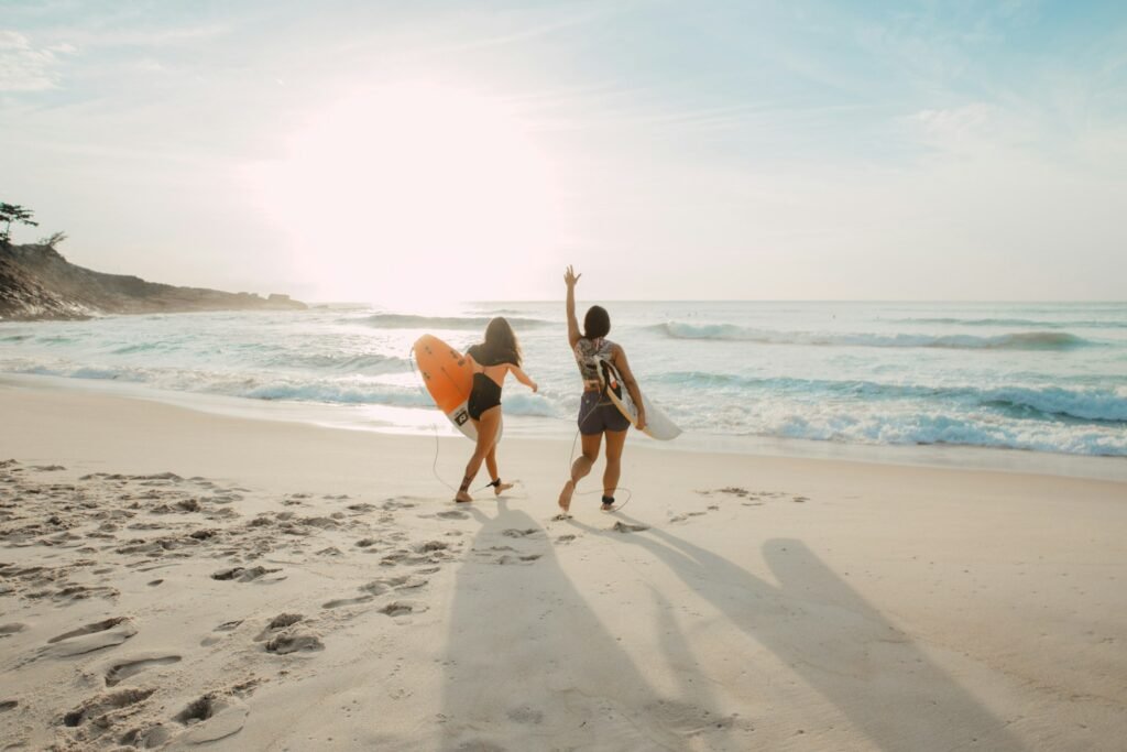 Duas mulheres entrando no mar para surfar