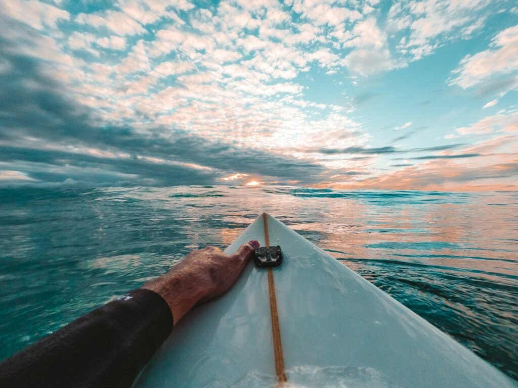Ponto de vista de um surfista em cima de sua prancha, no mar, olhando o por do sol